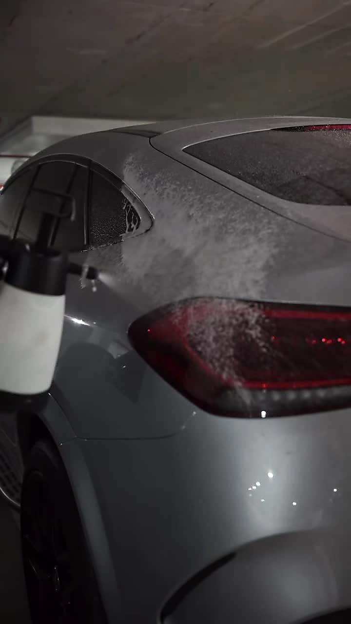 An operator applying the rinseless wash to a car in a garage at night